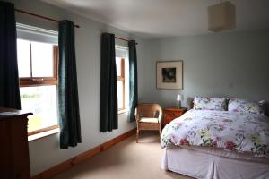 een slaapkamer met een bed, een stoel en ramen bij The White House in Enniskillen