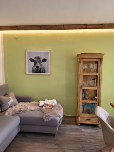 ein Wohnzimmer mit einem Sofa und einem Bild einer Kuh in der Unterkunft Ferienwohnung Schöne Auszeit in Oy-Mittelberg
