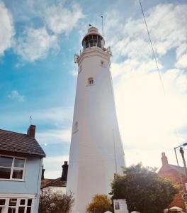 un phare blanc assis devant une maison dans l'établissement Charming 2 Bedroom Holiday Chalet, à Withernsea