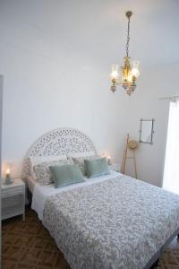 a bedroom with a white bed and a chandelier at Mimì Junior home, central sea view apartment in Praiano