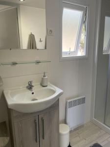 La salle de bains blanche est pourvue d'un lavabo et d'un miroir. dans l'établissement Blue Horizon, à Saint-Raphaël