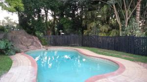 ein kleiner Pool in einem Garten mit einem Zaun in der Unterkunft Eagles Nest Guesthouse in Eshowe