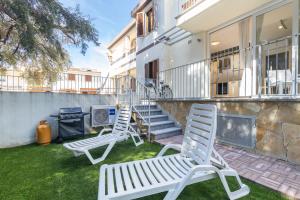 dos sillas blancas sentadas en un césped frente a una casa en Casa Olivastro Millenario B, en Santa Maria Navarrese