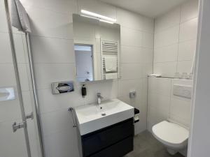a white bathroom with a sink and a toilet at Hotel Central in Bamberg