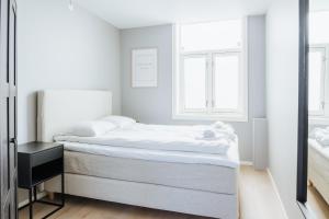 - une chambre blanche avec un lit et un miroir dans l'établissement Stay Strandgaten - New apartment in city center, à Bergen