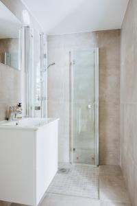 La salle de bains blanche est pourvue d'une douche et d'un lavabo. dans l'établissement Stay Strandgaten - New apartment in city center, à Bergen
