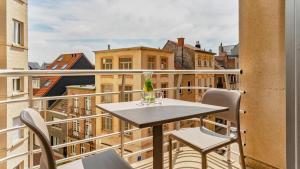 a table and chairs on a balcony with a view at Holiday Suites Blankenberge in Blankenberge