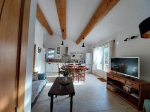 a living room with a couch and a tv and a table at Gîte Bienvenue Chez Nous in Ménerbes