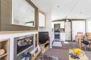 a living room with a television and a kitchen at Brilliant Caravan With A Partial Sea View In Suffolk Ref 32026az in Lowestoft