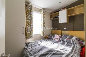 a small bedroom with a bed and a window at Brilliant Caravan With A Partial Sea View In Suffolk Ref 32026az in Lowestoft