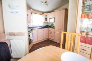 a kitchen with pink cabinets and a wooden table and a table sidx sidx at 8 Berth Caravan With Wifi And Decking In Lincs Ref 78003p in Winthorpe