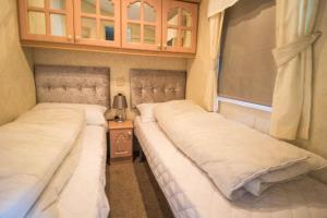 two beds in a small room with at 8 Berth Caravan With Wifi And Decking In Lincs Ref 78003p in Winthorpe