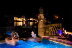 two people in a swimming pool at night at Hotel Villa e Palazzo Aminta in Stresa