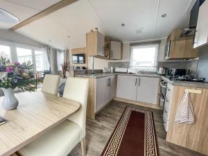 a kitchen with a table and a dining room at Beautiful Caravan For Hire With A Partial Sea View In Suffolk Ref 32042az in Lowestoft