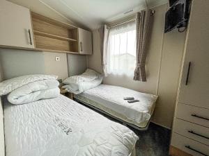 two beds in a small room with a window at Beautiful Caravan For Hire With A Partial Sea View In Suffolk Ref 32042az in Lowestoft