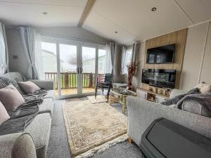 a living room with two couches and a tv at Beautiful Caravan For Hire With A Partial Sea View In Suffolk Ref 32042az in Lowestoft