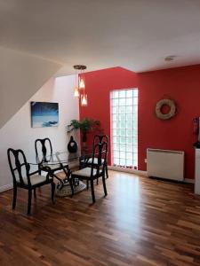 uma sala de jantar com uma mesa e cadeiras e paredes vermelhas em Village centre apartment em Lahinch