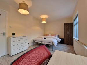 een slaapkamer met een bed en een rode stoel bij Nice Living Serviced Accommodations 6 in Birmingham