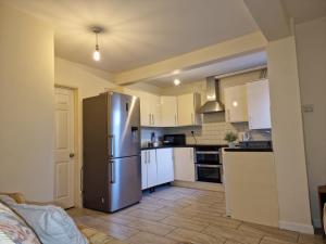 een keuken met een roestvrijstalen koelkast en witte kasten bij Nice Living Serviced Accommodations 6 in Birmingham