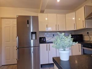 een keuken met een roestvrijstalen koelkast en witte kasten bij Nice Living Serviced Accommodations 6 in Birmingham