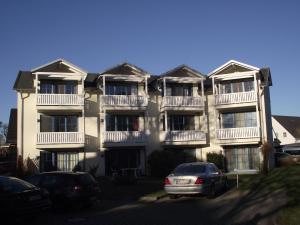 a large apartment building with cars parked in front of it at Ferienwohnung Möwe in Glowe