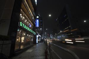 Una calle de la ciudad por la noche con coches conduciendo por la calle en K-Guesthouse Myeongdong 1 en Seúl