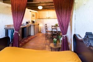 a bedroom with purple curtains and a kitchen with a table at Gite une belle Histoire in Voisey