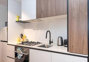 cocina blanca con fregadero y fogones en Relaxing Urban Oasis en Melbourne