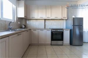 a kitchen with white cabinets and a stainless steel refrigerator at Elise Apartment Airport by Airstay in Spata