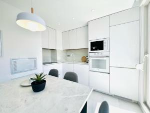 a kitchen with white cabinets and a table with a potted plant at Sunrise Center Suites in Torrevieja