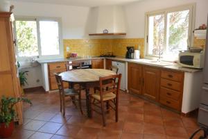Una cocina con mesa y sillas y un microondas. en Villa CAROLE Piscine privée Spa Fautéa, en Zonza