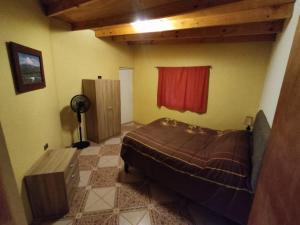 1 dormitorio con cama y cortina roja en Cabañas Larache en San Pedro de Atacama