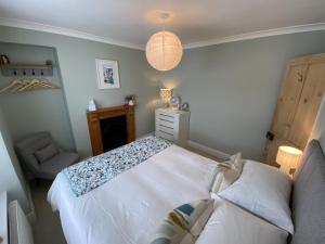 um quarto com uma cama branca e uma cadeira em Spacious, seaside, Victorian home "Bay View Terrace", Penzance em Penzance
