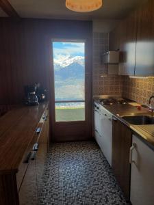 a kitchen with a door with a view of a mountain at La Crettaz SUNNY & QUIET apartment 6 pers by Alpvision Résidences in Veysonnaz