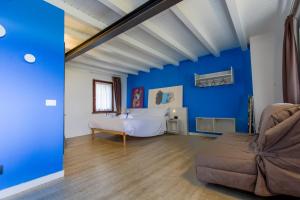 Habitación azul con cama y sofá en Le Tofane, vivi la bellezza di Belluno - Genziana, en Sòis