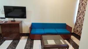 ein blaues Sofa im Wohnzimmer mit einem TV in der Unterkunft THE ROYAL RESIDENCY in Kushinagar
