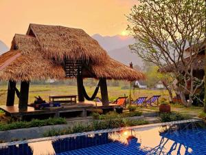 um resort com piscina e uma cabana com cadeiras em Buzzas @ Pai Chan em Pai