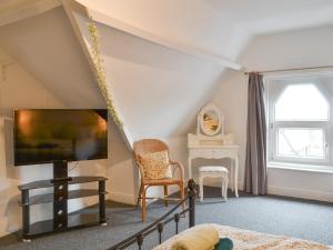 a bedroom with a flat screen tv and a chair at Brincliffe Loft in Bridlington