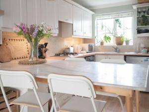 a kitchen with a large wooden table with white cabinets at Historic Malmesbury - Delightful home with parking in Malmesbury