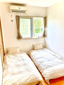 two beds in a small room with a window at お子様連れ&動物好き大歓迎！産みたての卵を収穫体験できる宿 in Nanjo