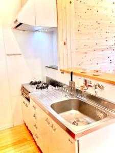 a kitchen with a sink and a stove at お子様連れ&動物好き大歓迎！産みたての卵を収穫体験できる宿 in Nanjo