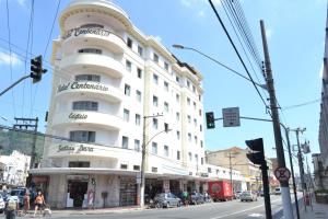 een wit gebouw in een stadsstraat met een verkeerslicht bij Hotel Centenário in Juiz de Fora