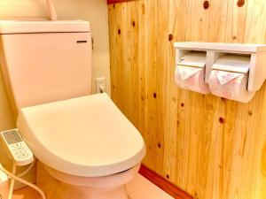 a bathroom with a white toilet and a telephone at お子様連れ&動物好き大歓迎！産みたての卵を収穫体験できる宿 in Nanjo