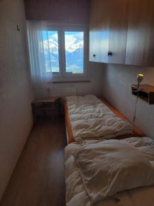 1 dormitorio con 2 camas y ventana en Mont Rouge VIEW & CENTER apartments by Alpvision Résidences, en Veysonnaz