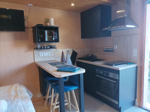 a small kitchen with a counter and a table with stools at Un petit coin de paradis in Orpierre