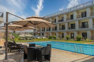 un hôtel avec une piscine et une table avec un parasol dans l'établissement Phoenix Apartment by LINK, à Kigali