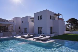 une villa avec une piscine en face d'une maison dans l'établissement Isida Andros, à Agios Petros