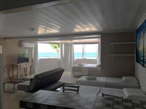 a living room with a couch and a bed and a window at Pousada Verdes Mares in Praia do Frances