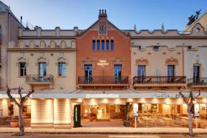 un gran edificio de ladrillo con un restaurante delante de él en Sercotel Kalma Sitges, en Sitges