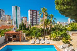 a pool with lounge chairs and a city skyline at Villa Cintya - PlusHolidays in Ifach